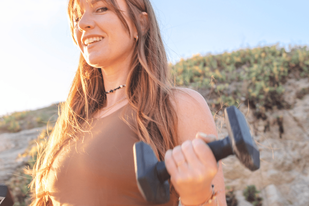 Morgane en séance de renforcement musculaire avec haltères sur la plage